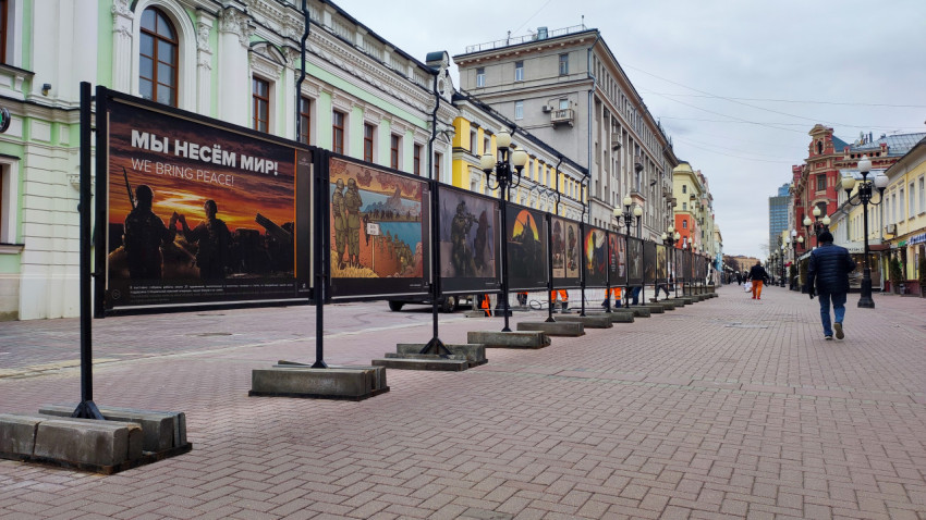 Мужчина идет по улице мимо фотовыставки