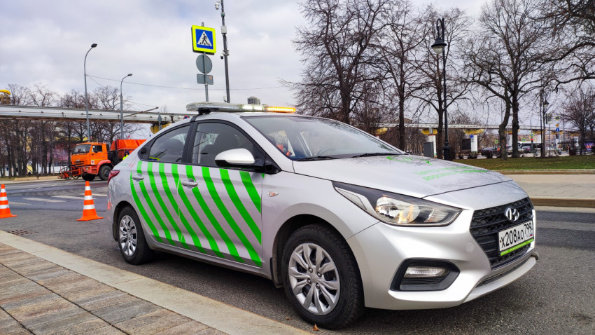 Серебряный автомобиль с зелеными полосами на обочине дороги