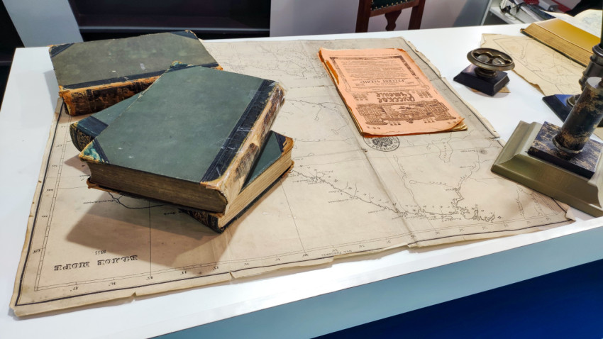 На столе разбросаны книги поверх древней карты