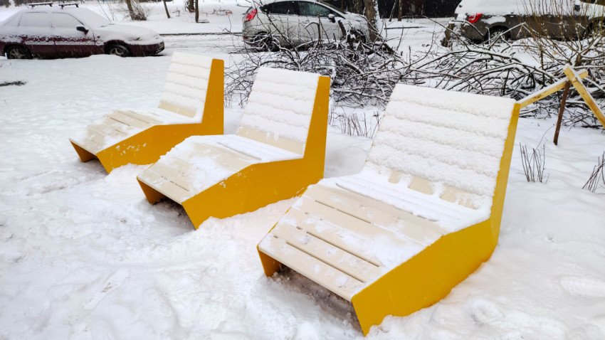 Зимние скамейки во дворе, покрытые снегом
