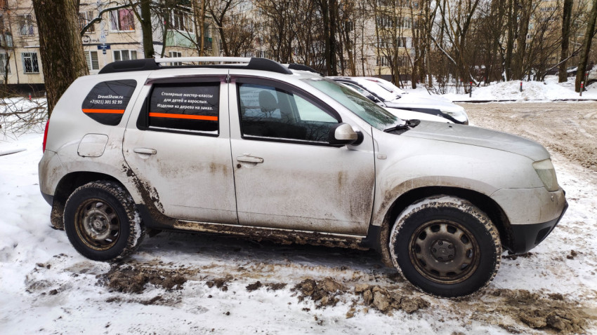 Загрязнённый автомобиль, припаркованный на снегу в городском дворе зимой