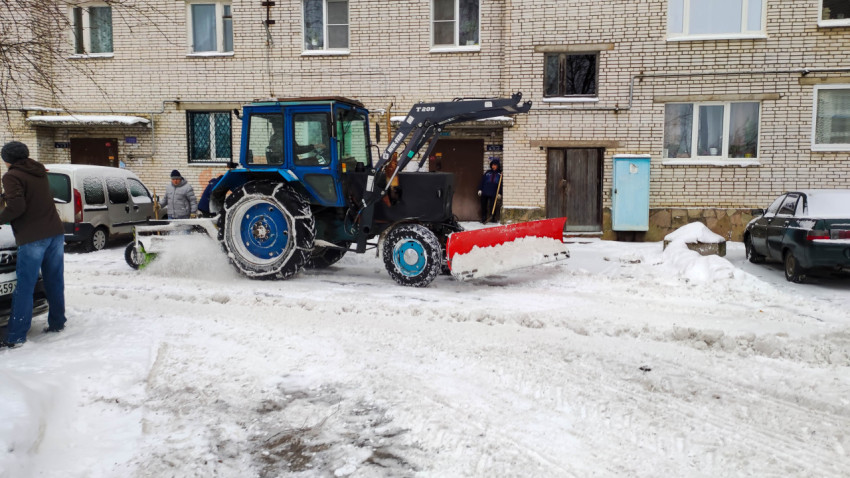 Очистка снега трактором во дворе жилого дома в зимний день