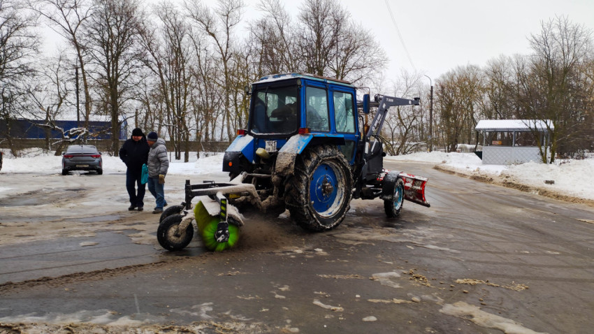 Снежная зима на улице, трактор очищает дорогу во дворе от снега