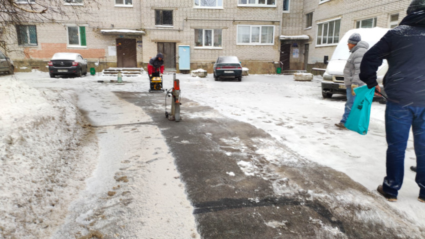 Ремонт дороги зимой во дворе жилого дома с работающей техникой и людьми