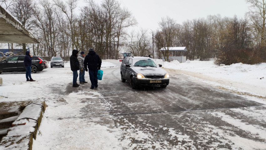 Автомобиль движется по очищенной дороге в снежный зимний день