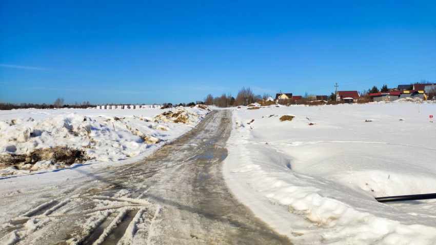Дорога, покрытая снегом, ведет к деревне под ясным небом