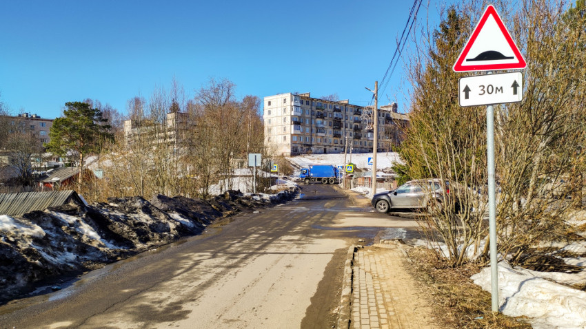 Дорога с растаявшим снегом и предупреждающим знаком о неровностях на дороге