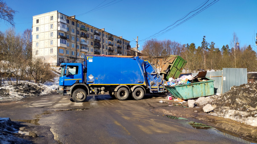 Мусоровоз собирает мусор у многоквартирного дома в солнечный день