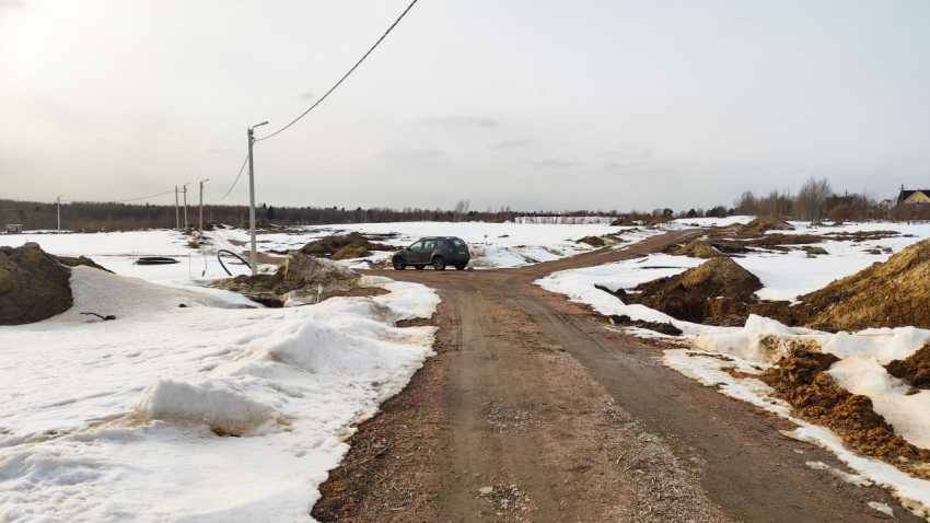 Дорога в поле с тающим снегом и автомобилем