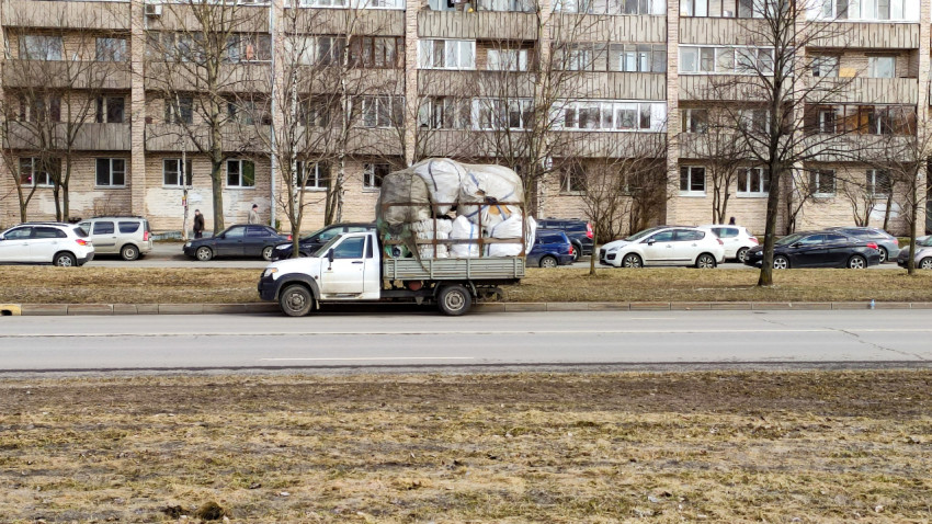 Газель с грузом проезжает мимо многоэтажек в городе