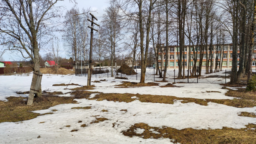 Весенний пейзаж с тающим снегом в парке рядом с домами
