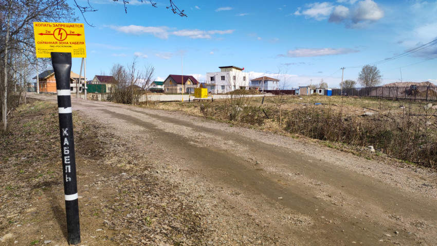 Столб, указывающий зону защиты кабелей, у дороги в пригороде