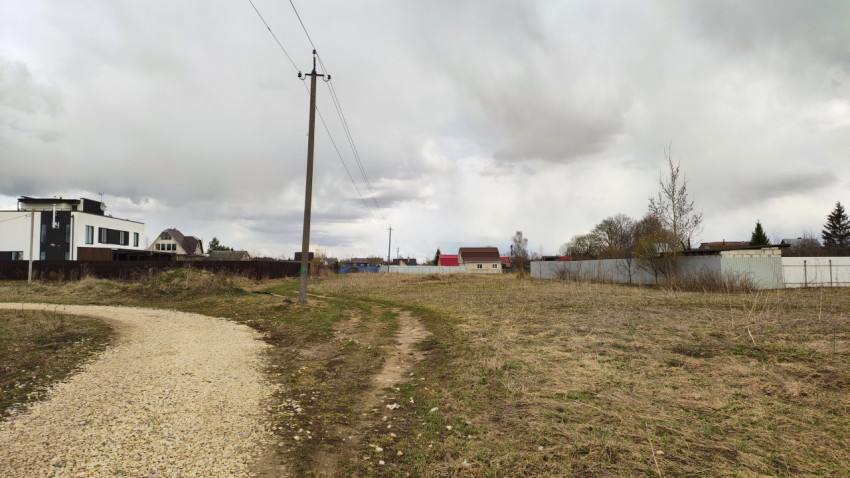 Участок земли в пригороде, облачное небо и электрические столбы