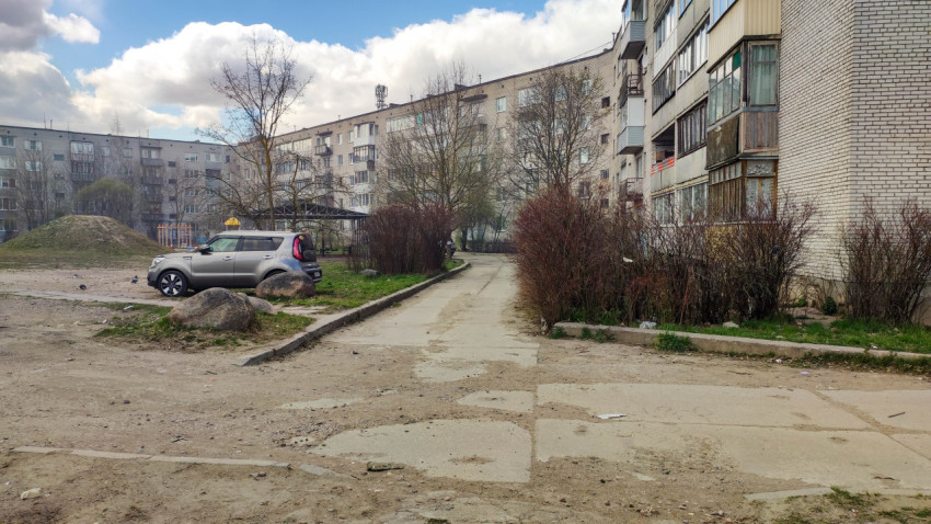 Двор жилого дома с автомобилем и кустами
