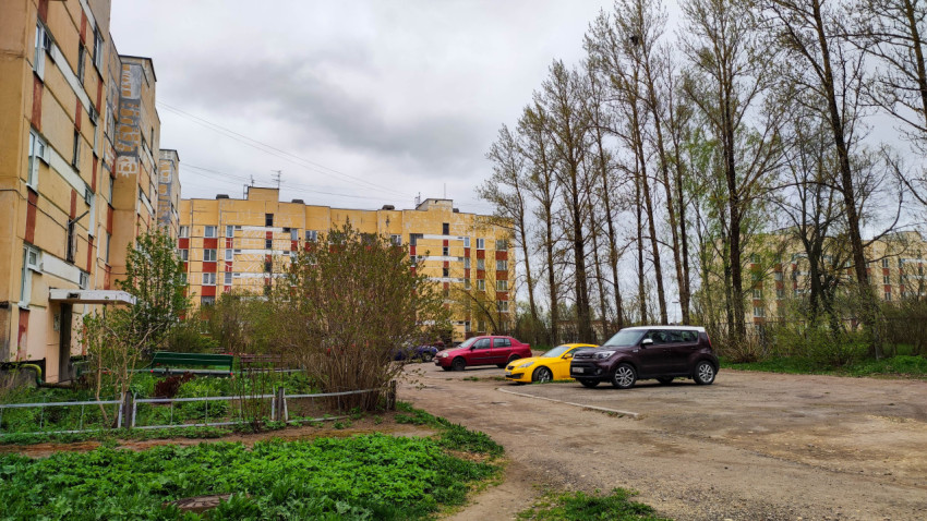 Двор многоквартирного дома с зелеными насаждениями и автомобилями