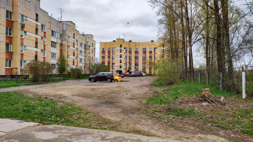 Двор жилого дома с парковкой и зелеными насаждениями