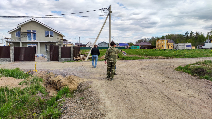 Люди идут по дороге в деревне с новыми домами