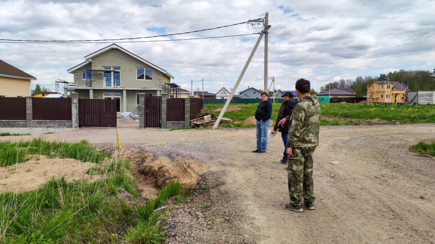 Люди на дороге в деревне с новыми домами на фоне строительства