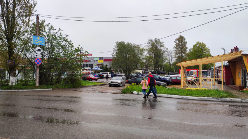 На улице в дождливую погоду два человека идут по мокрой дороге