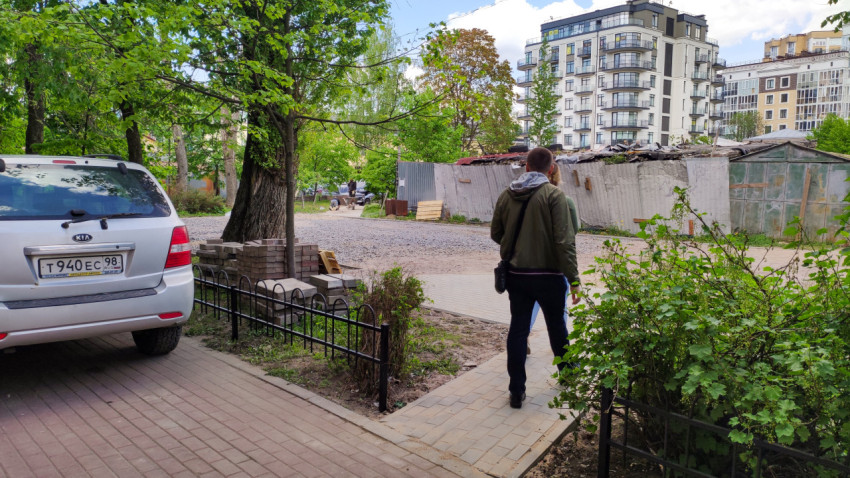 Человек гуляет по улице рядом с автомобилем и зелеными деревьями