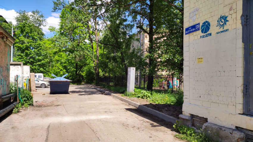 Пейзаж городской улицы с мусорным контейнером и зелеными деревьями