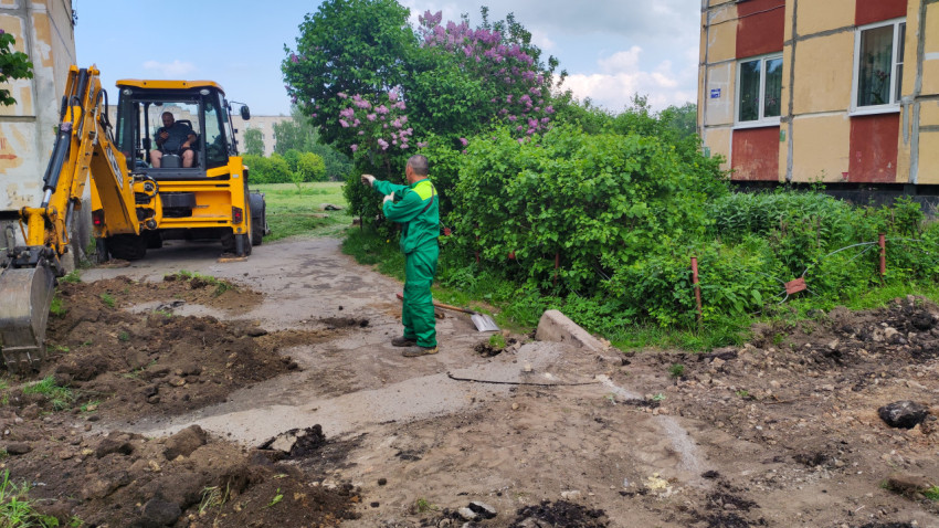 Рабочие проводят земляные работы рядом с многоквартирным домом