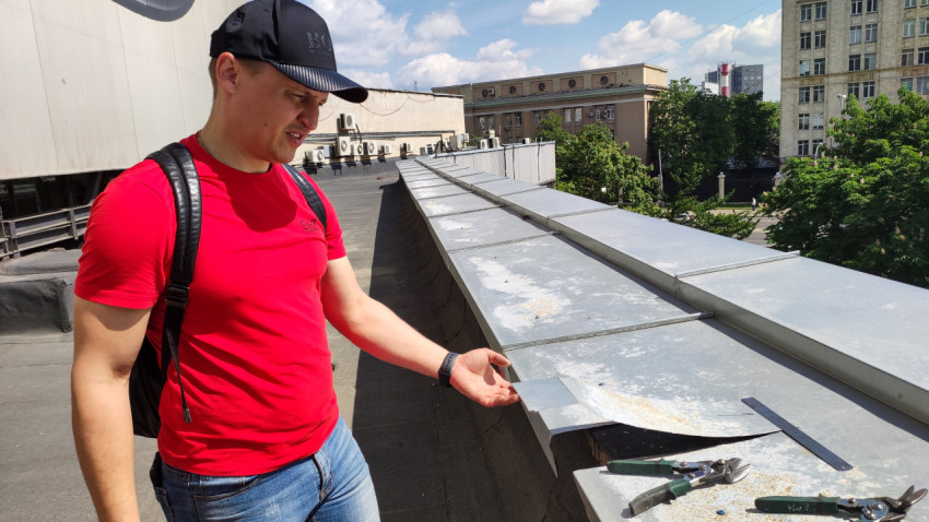 Молодой мужчина на крыше здания осматривает повреждение