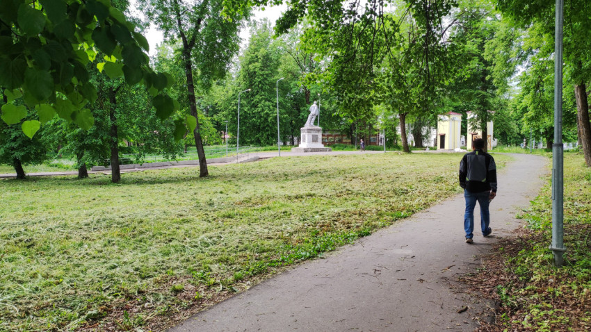 Пешеход в парке рядом с памятником на зеленом лугу