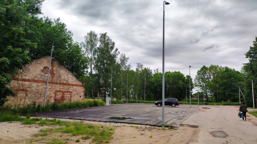Новая парковка для автомобилей рядом с заброшенным зданием