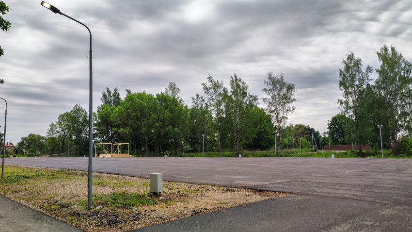 Новая парковка для автомобилей рядом с зелеными деревьями