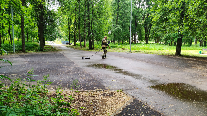 Мужчина с георадаром исследует территорию в парке