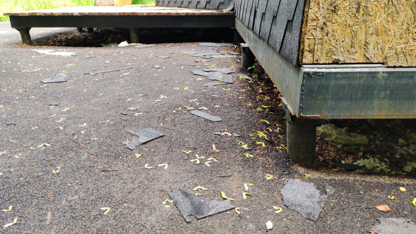Остатки гибкой битумной черепицы на асфальте возле строения