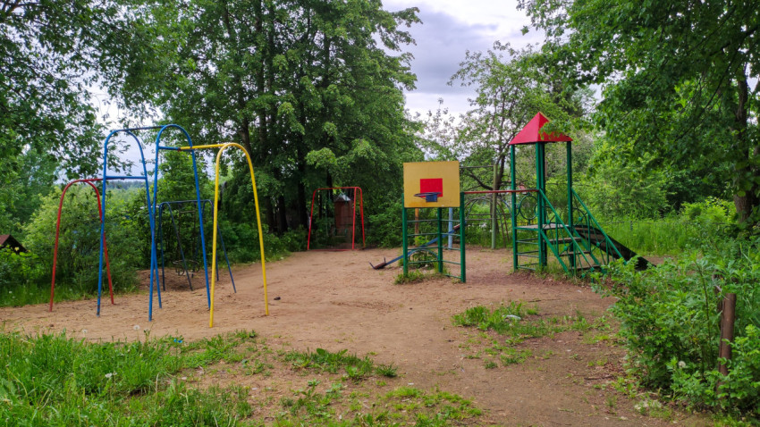Пустая детская площадка среди деревьев