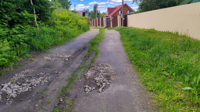 Грунтовая дорога с ямами и камнями в пригороде