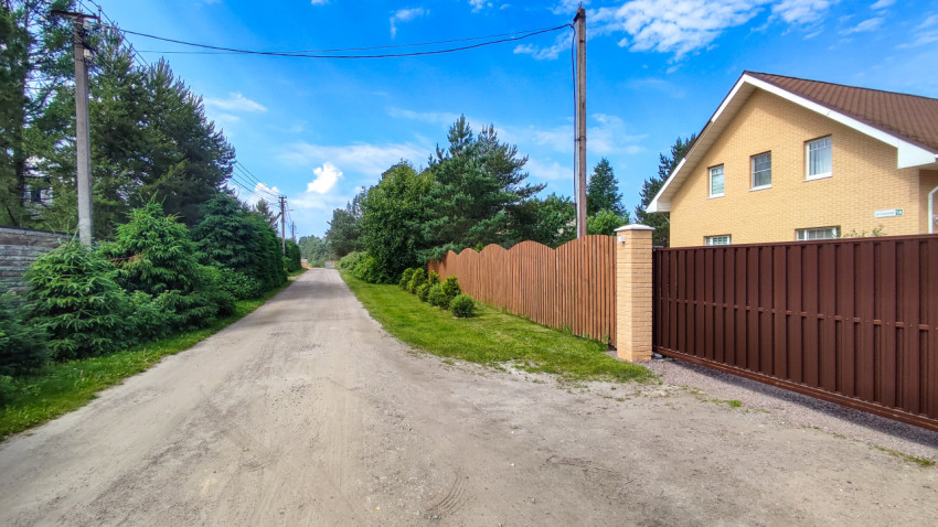 Уютная улица с домами и зеленью в загородной местности
