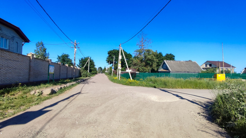 Перекресток в деревне с зелеными насаждениями и ясным небом