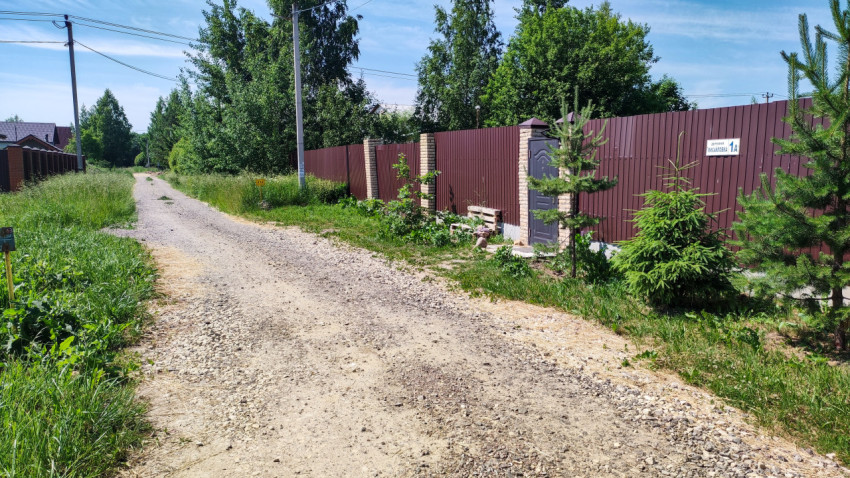 Загородная дорога вдоль забора в солнечный день