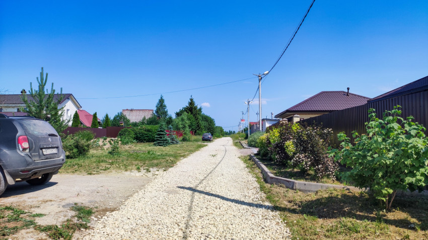 Загородная улица с гравийным покрытием и частными домами