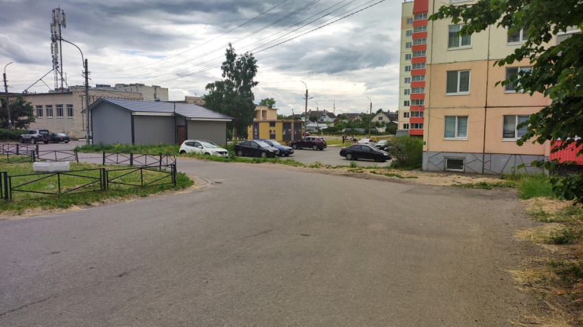 Улица в жилом районе с парковкой и облачным небом