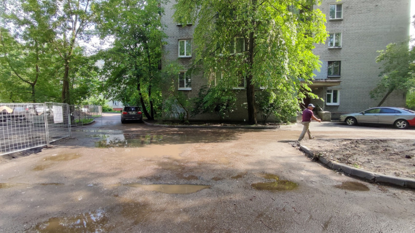 Лужи в ямах на дороге во дворе многоквартирного дома