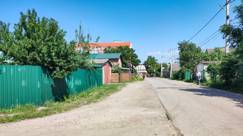 Спокойная улица с зелеными заборами в солнечный день