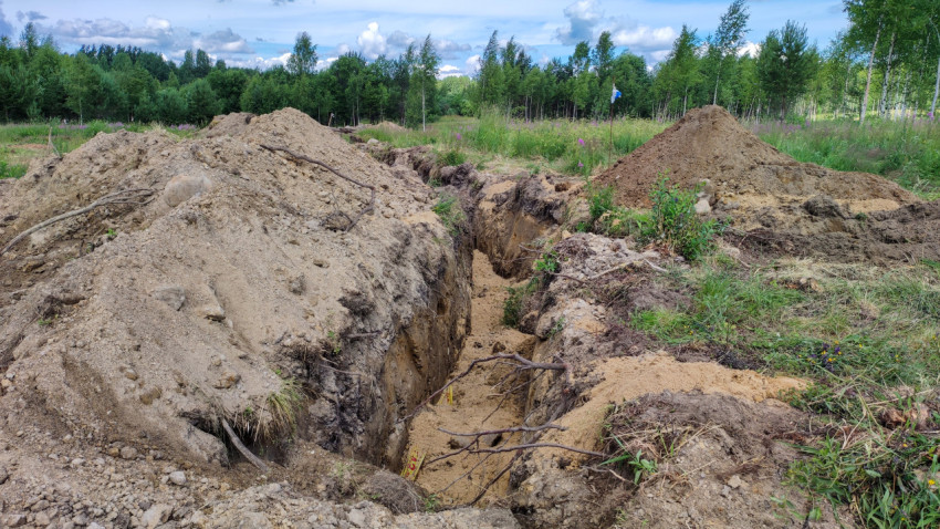 Выкопанная траншея для укладки труб на участке