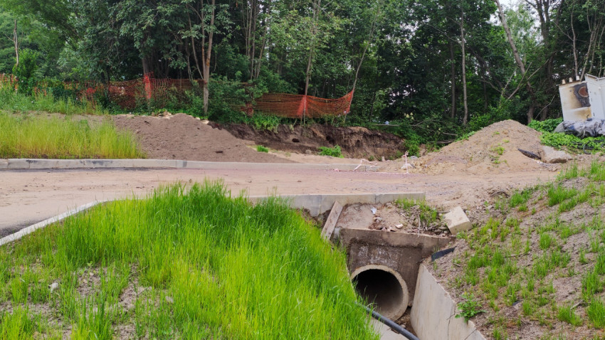 Подземный водосток под дорогой на зеленом участке