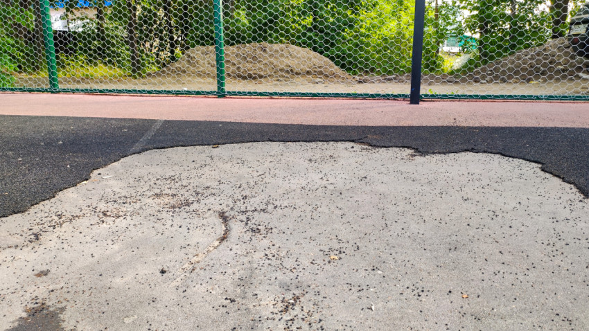 Поврежденное резиновое покрытие на баскетбольной площадке в парке