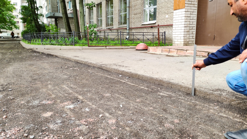 Измерение толщины асфальтового слоя на улице города на фоне здания