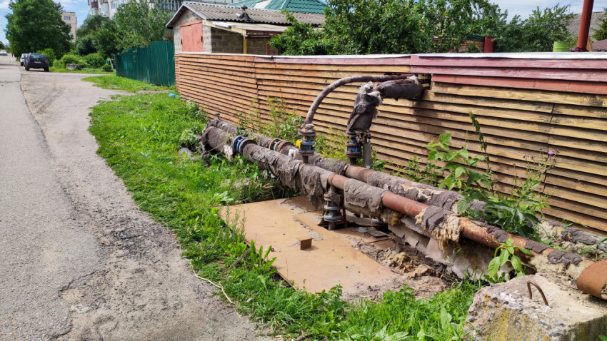 Трубопровод возле забора на городской улице