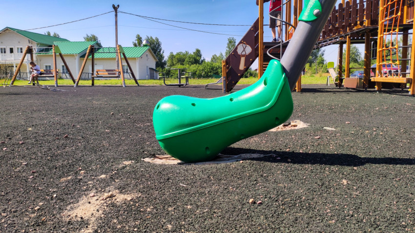 Повреждённое резиновое покрытие под карусельным балансиром на детской площадке