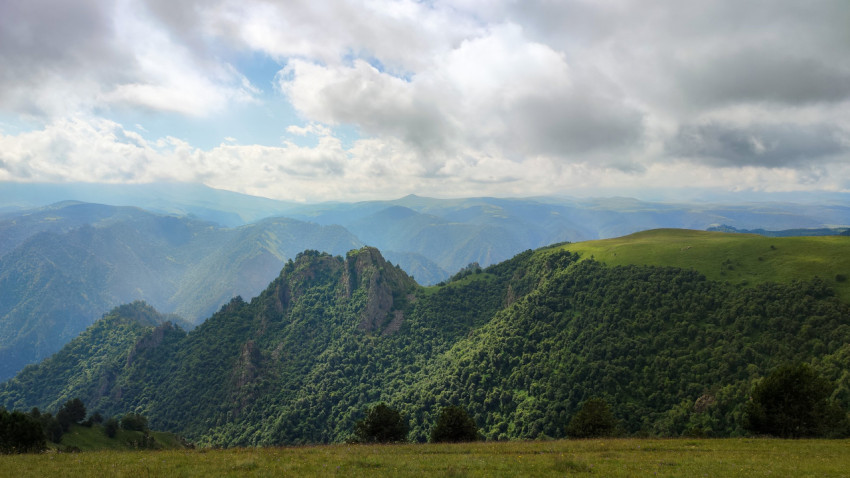 Красивая горная панорама с зелеными склонами и облачным небом