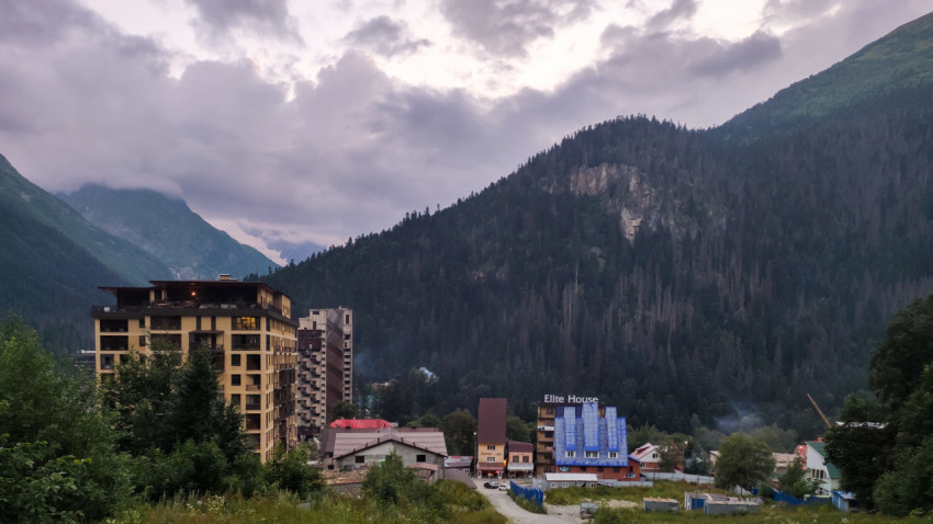 Горный пейзаж с современными зданиями и зелеными холмами