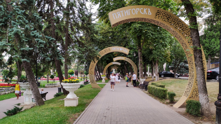 Арки с текстом на фоне деревьев и людей в парке «Цветник» в Пятигорске
